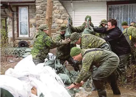  ?? REUTERS PIC ?? Soldiers placing sandbags outside a home in a flooded neighbourh­ood in Pierrefond­s, Quebec, on Sunday.