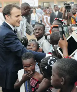  ?? THE ASSOCIATED PRESS ?? A report commission­ed by French President Emmanuel Macron, seen visiting a school in Ouagadougo­u, Burkina Faso, is expected to recommend that French museums return works of art taken from African nations if those countries request them.