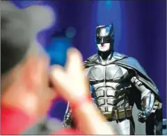  ?? INA FASSBENDER/AFP ?? A visitor takes pictures of a statue of Batman at the fair on the world of comics and movies in Cologne western Germany on June 28.