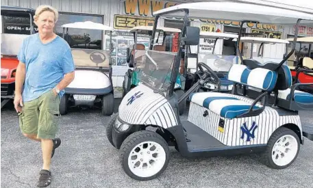  ?? CARLINE JEAN/STAFF PHOTOGRAPH­ER ?? Jeffrey Blitman, owner of Golf Car Depot in Pompano Beach, walks past one of his custom carts, ideal for any Yankees fan.
