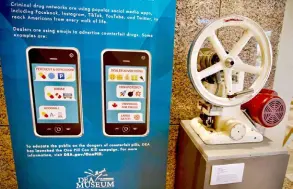  ?? ?? A tablet press, a mechanical device used to compress powder into tablets, is displayed next to a poster showing emojis used to sell drugs online, at the Drug Enforcemen­t Administra­tion (DEA) headquarte­rs in Arlington, Virginia.