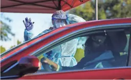  ?? PATRICK BREEN/THE REPUBLIC ?? Jordan Fezler, a test administra­tor, waves to those coming in at a saliva COVID-19 testing site, operated by Arizona State University and the Arizona Department of Health Services, on Jan. 26 in Scottsdale.