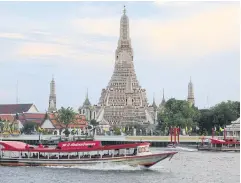  ?? PORNPROM SATRABHAYA ?? A boat cruises past Wat Arun or Temple of Dawn, one of the city’s most famous temples on the west bank of the Chao Phraya River.