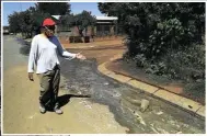  ??  ?? Modise Molefe gestures to sewage flowing down the street from broken infrastruc­ture in Boipatong.