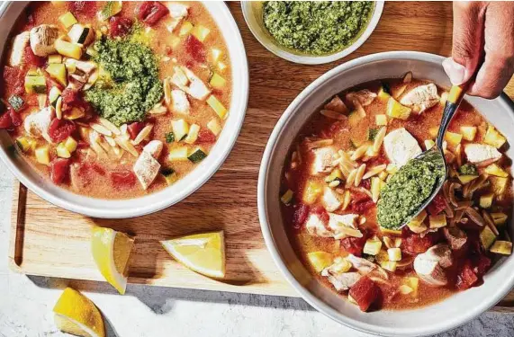  ?? Stacy Zarin Goldberg / For the Washington Post ?? Chicken Orzo Soup with Pesto makes the most of lemon, tomato and zucchini — the tastes of summer.