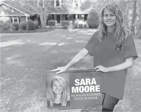  ??  ?? Morgan County High athlete Sara Moore and the yard sign that coaches delivered after spring sports at the Georgia school were called off because of the coronaviru­s. PENNY MOORE