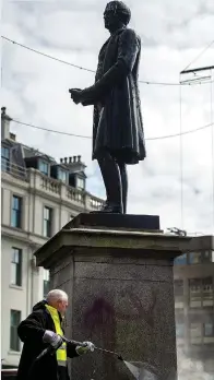  ??  ?? Defaced: A worker cleans Robert Peel statue