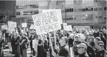  ??  ?? A man holds signs while listening during a downtown Vancouver rally in support of the pipeline expansion.