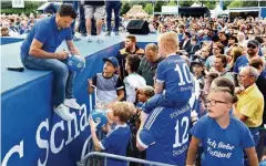  ??  ?? Basisarbei­t: Schalkes Manager Christian Heidel schreibt Autogramme für die kleinen Fans.