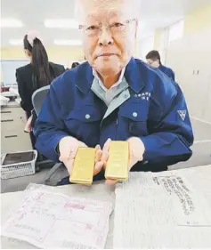  ??  ?? SURPRISE GIFT: Kunio Sunow shows off two slabs of gold each weighing one kilogramme as well as the parcel’s invoice (bottom left) and magazine article (bottom right) at his office in Ishinomaki, Miyagi prefecture. — AFP photo
