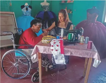  ?? L. MORA ?? Doña Maguito trabaja, desde su silla de ruedas, aplicando flores y detalles a los vestidos .