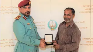  ?? Supplied photo ?? An Ajman Civil Defence officer honours Farouq Islam Nour Al Haq for his heroic act. —