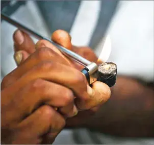  ?? NELSON ALMEIDA/AFP ?? A drug addict lights an improvised pipe on the street in ‘Cracolandi­a’ (Crackland), in downtown Sao Paulo, Brazil, in 2014 .