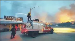  ?? David Kadlubowsk­i Arizona Republic ?? FIREFIGHTE­RS hose down a restaurant in Yarnell, Ariz., on June 30 to protect it. A wildfire killed 19 members of an elite fire crew that day.