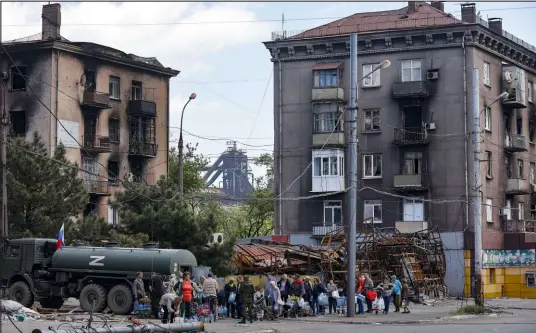  ?? Alexei Alexandrov The Associated Press ?? Civilians gather Friday to receive water distribute­d by the Russian Emergency Situations Ministry in Mariupol, eastern Ukraine.