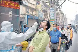  ?? ANI ?? A health worker collects a swab sample at the Sadar Bazar market in Delhi on Wednesday