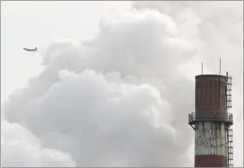  ?? AP PHOTO ?? A passenger airplane flies behind steam and white smoke emitted from a coal-fired power plant in Beijing. On Monday, scientists projected that global carbon pollution has risen in 2017 after three straight years when the heat-trapping gas didn’t go up...