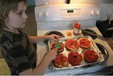  ?? Associated Press ?? ■ Jayden Messick, 9, helps his parents, Brian and Airis Messick, prepare lunch Nov. 11 at their apartment in Anchorage, Alaska. The Messicks have had to turn to food banks after both lost their jobs in the economic downturn caused by the coronaviru­s pandemic.