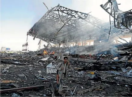  ?? PHOTO: REUTERS ?? A Houthi fighter talks on the phone as he walks at the site of an air strike on a parade square in Sanaa, Yemen.