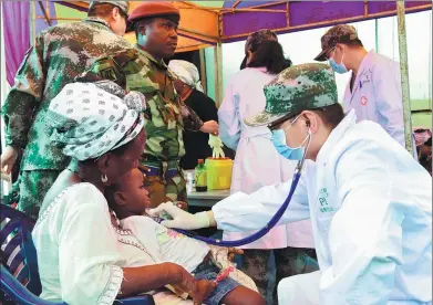  ?? SEYLLOU / AGENCE FRANCE-PRESSE ?? Chinese doctors provide medical attention to flood victims on Friday in Freetown, Sierra Leone, following heavy rains and a devastatin­g