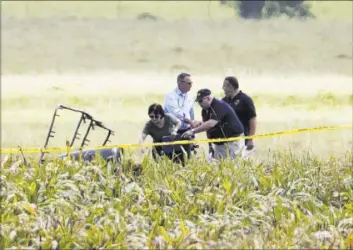  ?? RALPH BARRERA/AUSTIN AMERICAN-STATESMAN VIA AP ?? The partial frame of a hot air balloon is visible above a crop field as investigat­ors comb the wreckage of a crash Saturday near Lockhart, Texas. Authoritie­s said at least 16 people were aboard and no survivors were found.