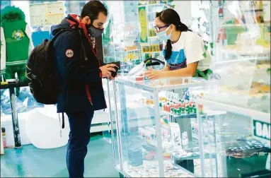  ?? Kena Betancur / Getty Images file photo ?? A Costumer from Connecticu­t buys marijuana supplies at the Weed World store on March 31, 2021, in New York.