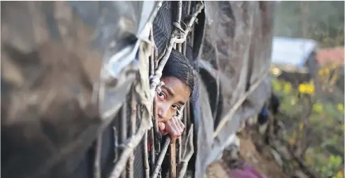  ?? MUNIR UZ ZAMAN / AFP / GETTY IMAGES ?? A Rohingya girl looks out from a shelter at a refugee camp in the Bangladesh district of Ukhia on Nov. 13.