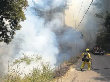  ?? PATRICK TEHAN/STAFF PHOTOS ?? Firefighte­rs battle flames that crossed Palo Colorado Road as the Soberanes fire burns Wednesday in the Carmel Highlands. The fire is continuing to grow and has scorched more than 23,000 acres and destroyed 20 homes since roaring to life Friday.