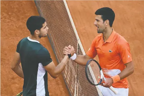  ?? AFP VIA GETTY IMAGES ?? Carlos Alcaraz and Novak Djokovic shake at the end of their Mutua Madrid Open semifinal Saturday. Alcaraz won in three sets to become the first player to defeat both Rafael Nadal and Djokovic at the same event on clay.