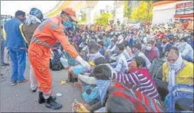  ?? AMAL KS/HT PHOTO ?? ■
A National Disaster Relief Force staff member offers hand sanitiser to migrant workers outside Anand Vihar Bus Terminus in New Delhi on Sunday.