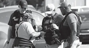  ?? ROGELIO SOLIS/AP ?? A registered immigrant shows federal agents his identifica­tion as he leaves the Koch Foods Inc. plant in Morton, Miss.