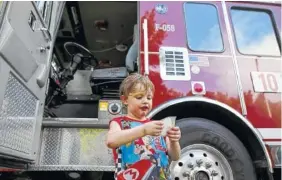  ??  ?? Left: Hamilton County Mayor Jim Coppinger reads the names of the Fallen Five during the Chattanoog­a Strong Community Concert on Sunday. Right: Four-year-old Jason Crowder holds the backing to a police badge sticker as he stands in front of a firetruck...