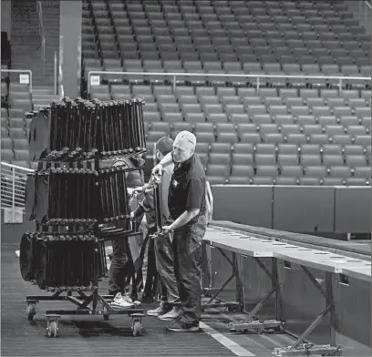  ?? AARON DOSTER/AP ?? Workers remove chairs from media row inside University of Dayton Arena on March 13, a day after the NCAA Tournament was canceled.