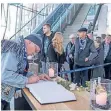  ??  ?? Trauernde Fans tragen sich in der Arena Auf Schalke ins Kondolenzb­uch für Assauer ein.