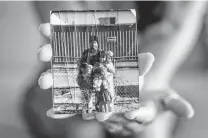  ??  ?? Alice Almendarez holds a photo of her father and herself, along with her sisters.