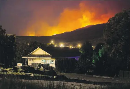  ??  ?? A wildfire burns on a mountain behind a recreation­al vehicle park office in Cache Creek on Saturday.