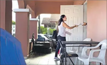  ?? Saul Martinez Getty Images ?? AN ACTIVIST goes door-to-door in Miami this month to warn about an immigratio­n enforcemen­t operation.