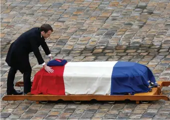  ??  ?? French President Emmanuel Macron leans at the coffin of Lt Col Arnaud Beltrame after he was posthumous­ly awarded the Legion of Honour yesterday at the Hotel des Invalides in Paris