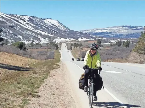  ?? STEVE HINIKER PHOTO ?? Mary Ellen Vollbrecht cycles against a backdrop of late-season snow in the Rockies outside of Pegosa Springs, Colo. Vollbrecht and her husband, Steve Hiniker, cycled 7,000 miles across three continents after Steve retired.