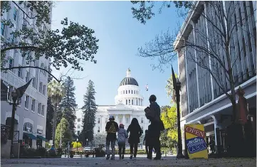  ??  ?? Pedestrian­s pass the California State Capitol building in Sacramento.