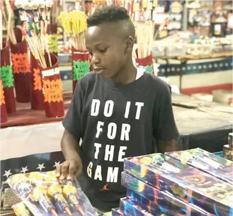  ?? (Photo by Mary Rumore, SDN) ?? Jordan Washington, 11, shops for fireworks at Orbit Fireworks on Highway 182 in Starkville on Monday.