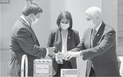  ?? JOE BURBANK/ORLANDO SENTINEL ?? Vice President Mike Pence signs PPE packages with Gov. Ron DeSantis and Seema Verma, administra­tor of the Centers for Medicare and Medicaid Services, in Orlando on Wednesday.