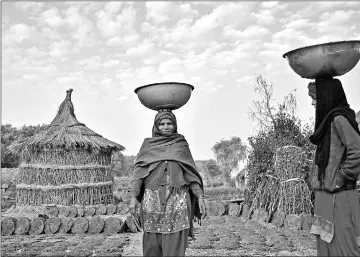  ??  ?? Women carry containers of cow dung on their heads at a village in Palwal district, Haryana. — Bloomberg photos by Anindito Mukherjee