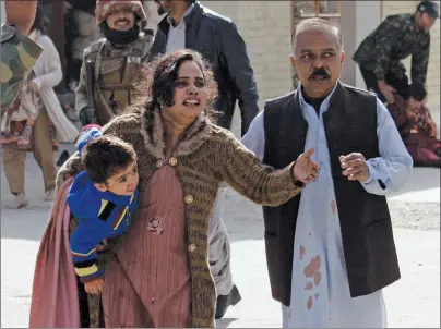  ?? AP PHOTO ?? A man helps an injured woman and a child following an attack on a church in Quetta, Pakistan, Sunday. Two suicide bombers attacked the church when hundreds of worshipper­s were attending services ahead of Christmas.