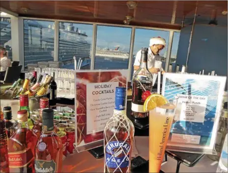  ?? JANET PODOLAK — THE NEWS-HERALD ?? Other ships in port at Fort Lauderdale are reflected in the window behind a bartender offering holiday-themed drinks to Zuiderdam passengers as the ship prepares to sail away.