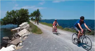  ??  ?? Bicyclists ride on the Island Line Trail bike path on an abandoned railroad causeway from the Vermont mainland to the Lake Champlain islands.