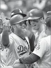  ?? JEFF ROBERSON/AP ?? The bearded Justin Turner slaps hands with manager Dave Roberts after hitting a two-run homer in the eighth.