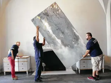  ?? Elizabeth Conley photos / Houston Chronicle ?? Teena Caldwell of Twenty-Two Fifty Interiors watches Luis Aguilera, left, and Job Sanchez place a painting onto a mantel as members of the American Society of Interior Designers sets up this year’s show house.