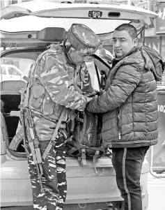  ??  ?? An Indian policeman searches a Kashmiri man and his backpack next to a car’s opened trunk in Srinagar. — AFP photo