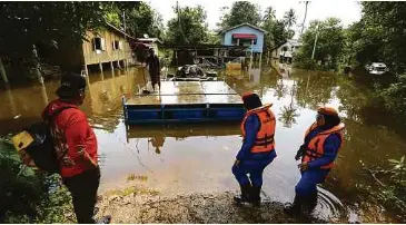  ?? ?? Anggota APM Rantau Panjang meninjau sebahagian rumah penduduk yang mula ditenggela­mi banjir di Kampung Tersang, semalam.